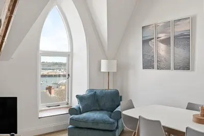 a living room with a blue chair and a window at Penthouse Apartment with Sea Views Falmouth in Falmouth