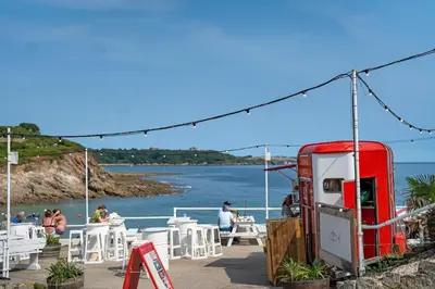 a red gas station next to a beach with people at Penthouse Apartment with Sea Views Falmouth in Falmouth