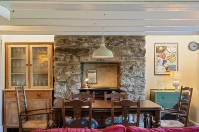a dining room with a table and a stone wall at 19th Century Cottage & Garden Private Parking in Perranporth