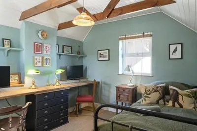 a living room with a desk and a couch at 19th Century Cottage & Garden Private Parking in Perranporth