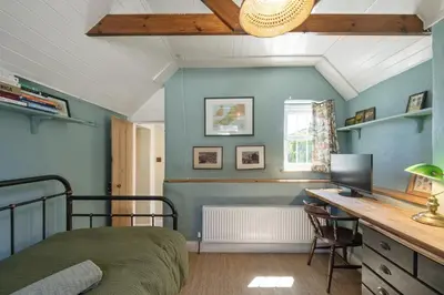 a bedroom with a bed and a desk with a computer at 19th Century Cottage & Garden Private Parking in Perranporth