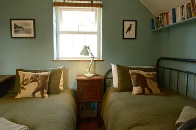 a bedroom with two beds and a window at 19th Century Cottage & Garden Private Parking in Perranporth
