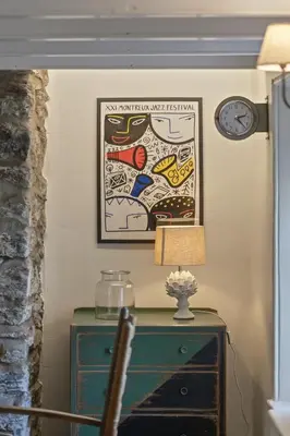 a table with a lamp and a clock on a wall at 19th Century Cottage & Garden Private Parking in Perranporth