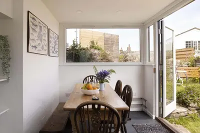 a dining room with a table and chairs and a window at Cottage & Boatshed in Gorran Haven Private Parking in Gorran Haven
