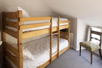 a couple of bunk beds in a room with a chair at Cottage & Boatshed in Gorran Haven Private Parking in Gorran Haven