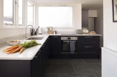 a kitchen with black cabinets and carrots on a counter at Cottage & Boatshed in Gorran Haven Private Parking in Gorran Haven