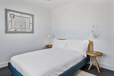 a white bedroom with a bed with a mirror at Beach House with Stunning Sea Views in Portreath