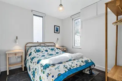 a bedroom with a bed and two windows at Beach House with Stunning Sea Views in Portreath