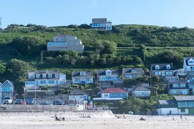 a group of houses on a hill next to a beach at Beach House with Stunning Sea Views in Portreath