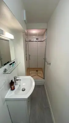 a white bathroom with a shower and a sink at Retro Ocean View Pad by Fistral Beach in Newquay