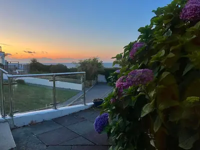 a view of the ocean from a balcony with purple flowers at Retro Ocean View Pad by Fistral Beach in Newquay