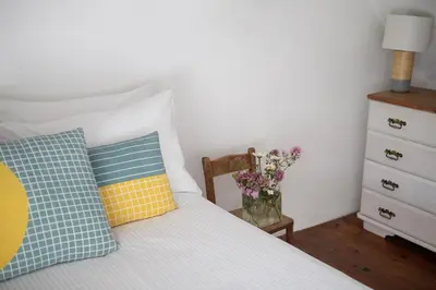 a bedroom with a bed with pillows and a vase of flowers at Old Cottage 1 min from the sea! Crackington Haven in Crackington Haven
