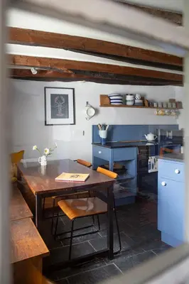 a kitchen with a wooden table and blue cabinets at Old Cottage 1 min from the sea! Crackington Haven in Crackington Haven