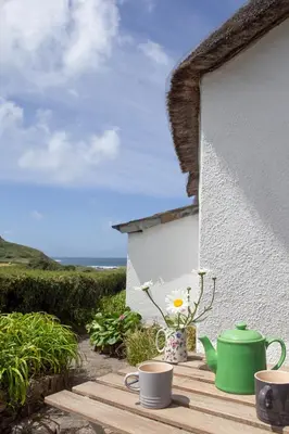 a table with two cups and a green tea pot on it at Old Cottage 1 min from the sea! Crackington Haven in Crackington Haven