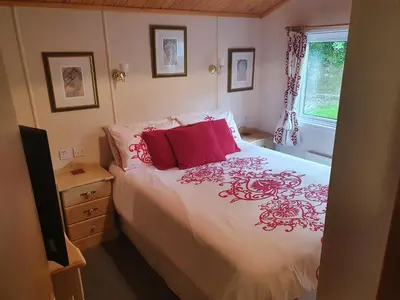 a bedroom with a bed with red pillows and a window at The Retreat in Polperro