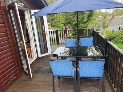 a table and chairs on a porch with an umbrella at The Retreat in Polperro