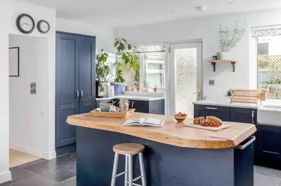 a kitchen with blue cabinets and a wooden counter top at Parkland Place - Spacious Newquay family holiday home, parking, log burner, dog friendly in Saint Columb Minor