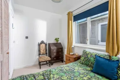 a bedroom with a bed and a chair and a window at Parkland Place - Spacious Newquay family holiday home, parking, log burner, dog friendly in Saint Columb Minor