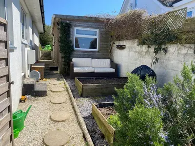 a small garden with a couch in a backyard at Parkland Place - Spacious Newquay family holiday home, parking, log burner, dog friendly in Saint Columb Minor