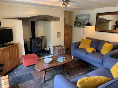 a living room with a blue couch and a fireplace at A Room In Coombe in Truro