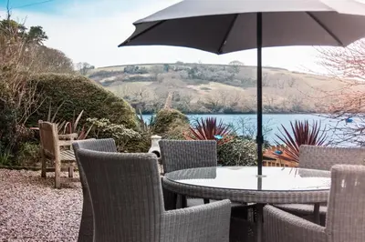 a table and chairs with an umbrella on a patio at A Room In Coombe in Truro