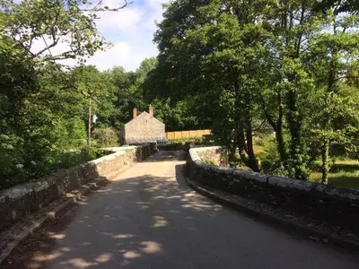 an empty road with a building and trees on the side at Hollyhocks Cottage surrounded by beautiful Cornish countryside. in Helland