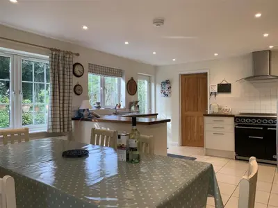 a kitchen with a table with a bottle of wine on it at Hollyhocks Cottage surrounded by beautiful Cornish countryside. in Helland