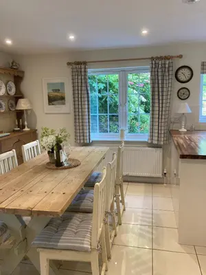 a kitchen and dining room with a wooden table and chairs at Hollyhocks Cottage surrounded by beautiful Cornish countryside. in Helland