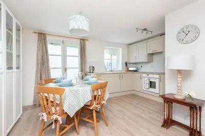 a kitchen with a table with chairs and a clock at Chapel Cottage St Mawgan on the Cornish coastline in Saint Mawgan