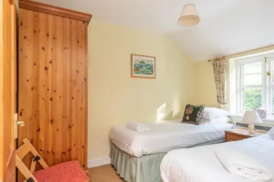 a bedroom with two beds and a wooden wall at Chapel Cottage St Mawgan on the Cornish coastline in Saint Mawgan