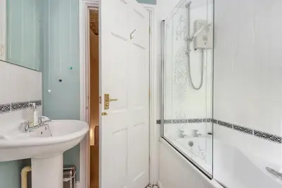 a white bathroom with a sink and a shower at Chapel Cottage St Mawgan on the Cornish coastline in Saint Mawgan