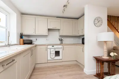 a kitchen with white cabinets and a clock on the wall at Chapel Cottage St Mawgan on the Cornish coastline in Saint Mawgan