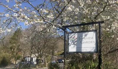 a sign for a garden with white flowers on a tree at Chapel Cottage St Mawgan on the Cornish coastline in Saint Mawgan