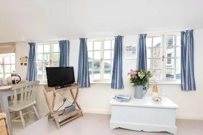 a living room with blue curtains and a television at Harbour Loft Port Isaac harbour beach views in Port Isaac