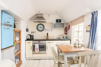 a kitchen with a table and a clock on the wall at Harbour Loft Port Isaac harbour beach views in Port Isaac