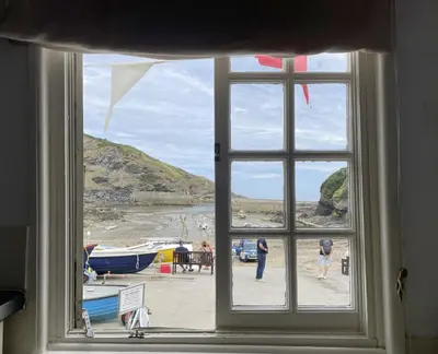 a window with a view of a beach with boats at Harbour Loft Port Isaac harbour beach views in Port Isaac
