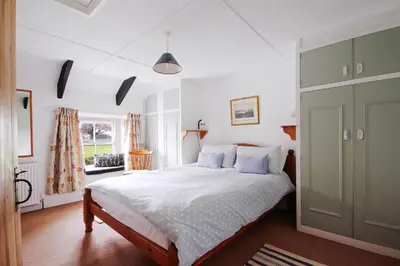 a bedroom with a bed and a green cabinet at Crotchet Cottage near sandy beach at Porthbeor in Saint Anthony