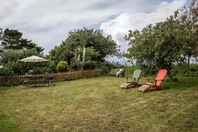 a yard with two chairs and a table and an umbrella at Crotchet Cottage near sandy beach at Porthbeor in Saint Anthony
