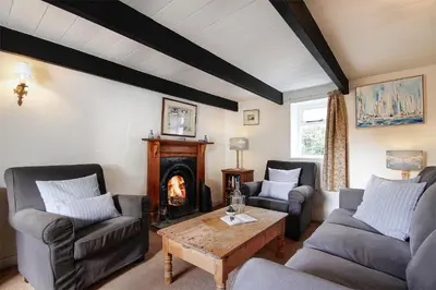 a living room with two couches and a fireplace at Crotchet Cottage near sandy beach at Porthbeor in Saint Anthony