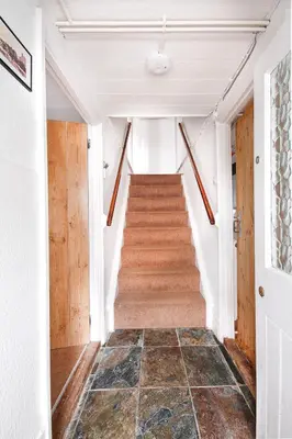 a hallway with a staircase in a house at Crotchet Cottage near sandy beach at Porthbeor in Saint Anthony