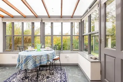 a conservatory with a table and chairs and windows at Tinners Forge a pretty cottage near Mevagissey in St Austell