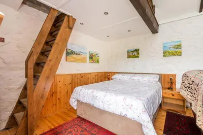 a bedroom with a bed and a ladder at Tinners Forge a pretty cottage near Mevagissey in St Austell