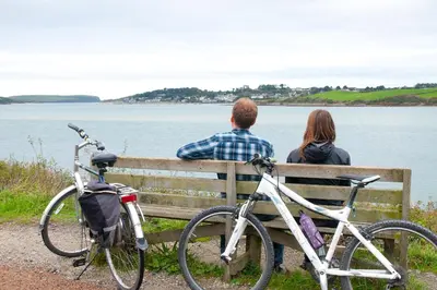 a man and a woman sitting on a bench with bikes at Hay Barn St Breock beautiful countryside views in Wadebridge