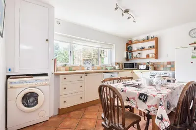 a kitchen with a table and a washing machine at Fernleigh Cottage near the North Cornish beaches in Saint Mabyn