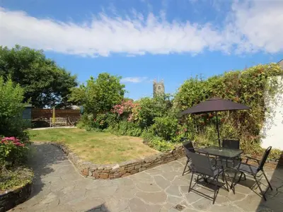 a patio with a table and chairs and an umbrella at Fernleigh Cottage near the North Cornish beaches in Saint Mabyn