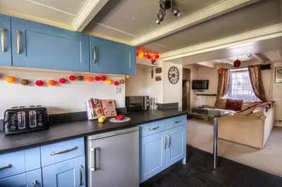 a kitchen with blue cabinets and a living room at Fourways near the golden sands of Marazion in Leedstown
