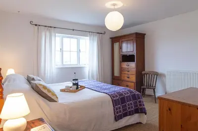 a bedroom with a bed and a dresser and a window at Carneggan Barn Lanteglos has breath taking views in Lanteglos