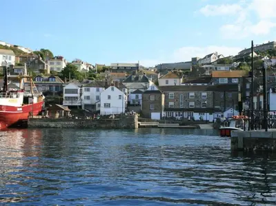 a boat is docked in a harbor with houses at Carneggan Barn Lanteglos has breath taking views in Lanteglos