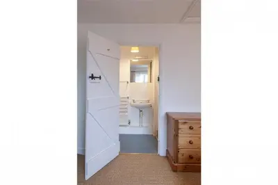 a bathroom with a door leading to a sink at Carneggan Barn Lanteglos has breath taking views in Lanteglos