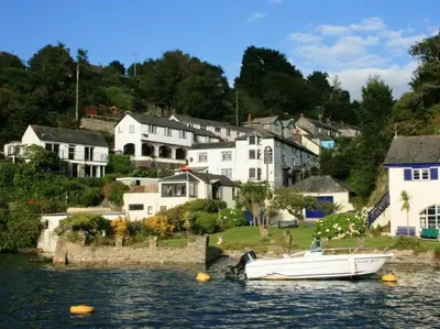 a white boat in the water in front of houses at Carneggan Barn Lanteglos has breath taking views in Lanteglos